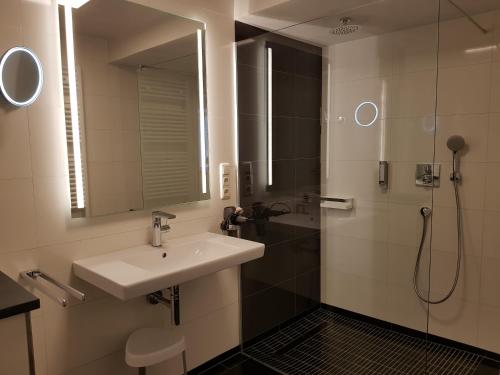 a bathroom with a sink and a shower with a mirror at Hotel Restaurant Alte Stadtmauer in Beilstein