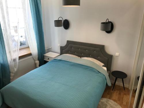 um quarto com uma cama com lençóis azuis e uma janela em Apartament Na Piwnej em Gdańsk