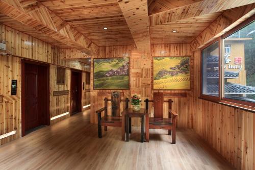 a wooden room with two chairs and a table in it at Baike Boutique Hotel in Longsheng