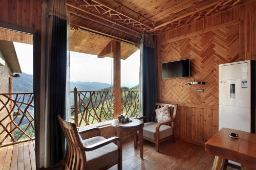 a room with a table and chairs and a large window at Baike Boutique Hotel in Longsheng