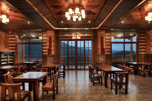 a restaurant with wooden tables and chairs and windows at Baike Boutique Hotel in Longsheng