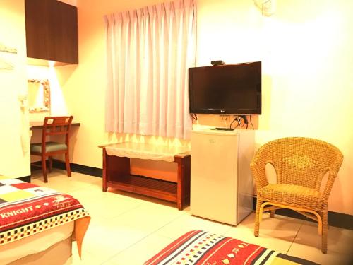 a hotel room with a television and a chair at Nan Wan KiKi Guesthouse in Nanwan