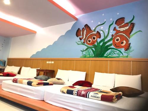 two beds in a room with a painting on the wall at Nan Wan KiKi Guesthouse in Nanwan