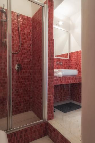 a red tiled bathroom with a shower and a mirror at Hello Gaeta Apartment in Gaeta