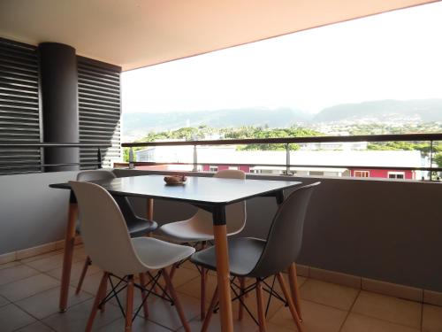 a table and chairs in a room with a view at Airport Appart in Sainte-Clotilde