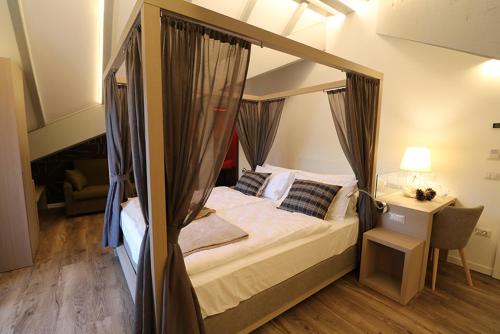 a bedroom with a canopy bed with a table and a chair at Hotel Florida in Levico Terme