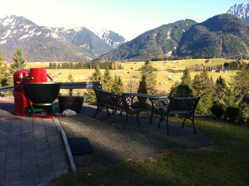 two benches and a grill with mountains in the background at Bäckeralm© - B&B 16 + in Mittenwald