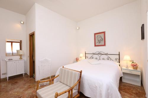 a bedroom with a white bed and a chair at villa oliveta in San Gimignano