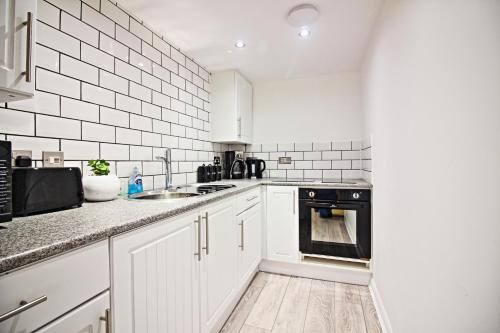 a white kitchen with a sink and a stove at Star Apartment in Ipswich