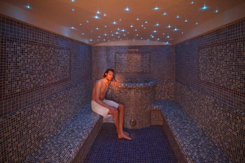a man sitting on a bench in a tiled room at Adults only Hotel Grafenstein in Schenna