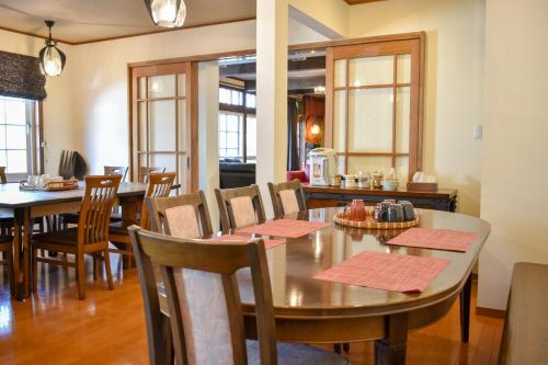 uma sala de jantar com mesas, cadeiras e janelas em Mojo Lodge Hakuba em Hakuba