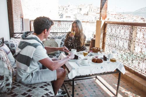 un hombre y una mujer sentados en una mesa comiendo comida en Riad-Boutique Borj Dhab Fez, en Fez