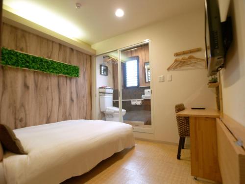 a bedroom with a bed and a television and a bathroom at Guesthouse Nara Komachi in Nara