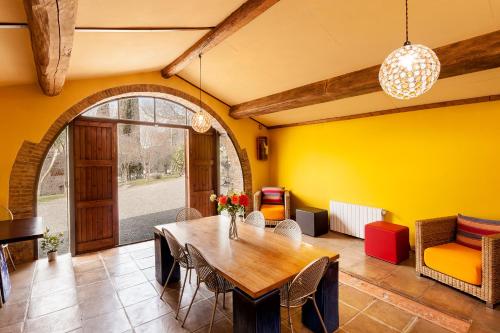 ein Esszimmer mit einem Tisch und einer gelben Wand in der Unterkunft Massa Vecchia in Massa Marittima