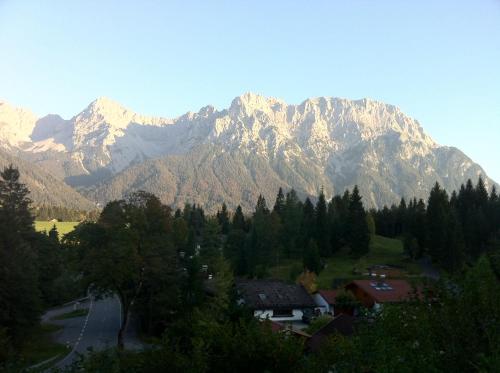 a mountain range with a road in front of a village at Bäckeralm© - B&B 16 + in Mittenwald