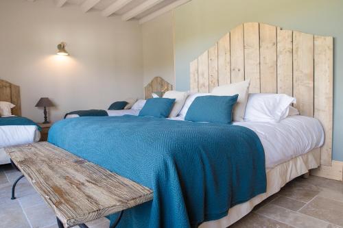 a bedroom with a large bed with a blue blanket at Domaine de Gailhaguet B&B in Verfeil