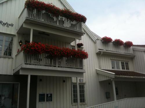 a building with red flowers on a balcony at Holsthuset Losji in Grimstad