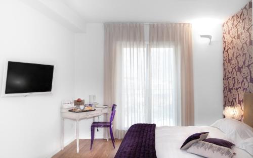 Dormitorio con cama, escritorio y TV en Spluga Sosta & Hotel, en Dubino