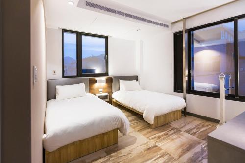 two beds in a room with two windows at Greatt Hotel in Taipei