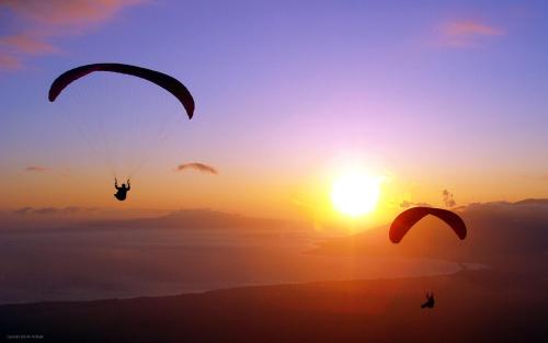 two people parasailing in front of a sunset at Sakura Hostel Fethiye in Fethiye