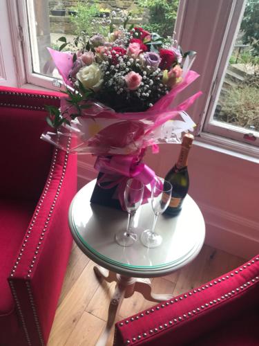 a table with a bouquet of flowers and a bottle of wine at The Haymarket Hotel in Edinburgh