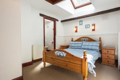 a bedroom with a wooden bed with blue pillows at Three Gates Farm Holiday Cottages in Huntsham