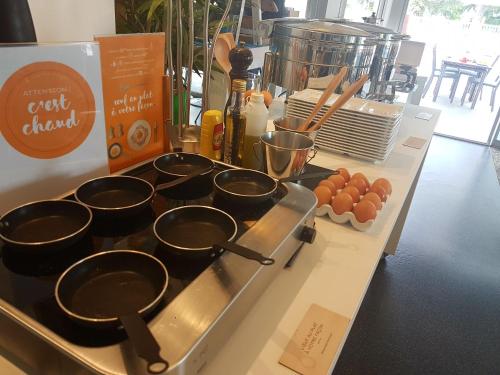 a bunch of pots and pans on a counter with eggs at Novotel Toulouse Purpan Aéroport in Toulouse
