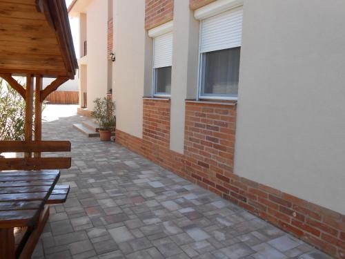 a brick patio with a bench and a building at Imola és Andrea Apartmanház 2 in Hajdúszoboszló