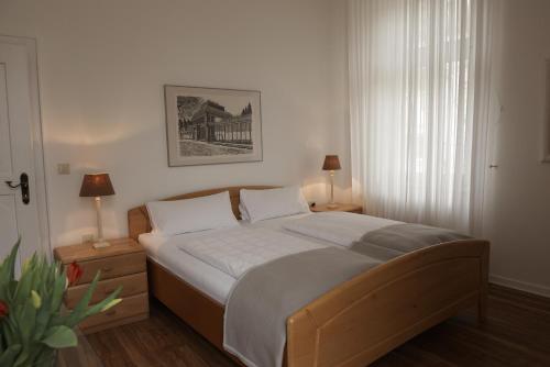 a bedroom with a bed and two lamps and a window at Hotel Burgfeld in Kassel