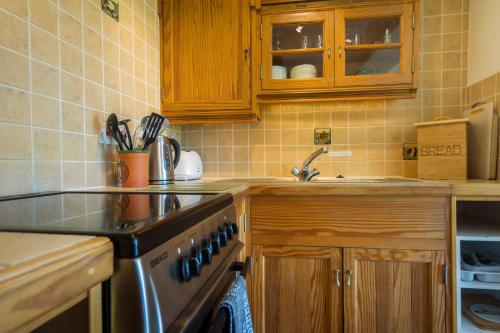 a kitchen with wooden cabinets and a stove top oven at Three Gates Farm Holiday Cottages in Huntsham