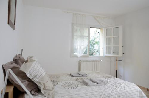 une chambre blanche avec un lit et une fenêtre dans l'établissement Mas du Puech Clapas, à Assas