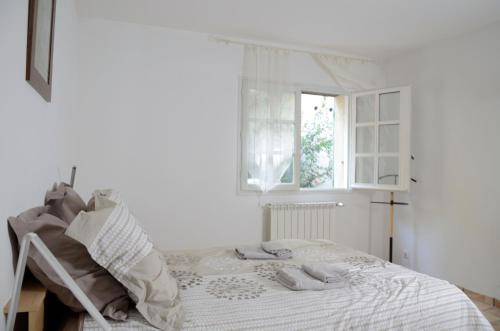 a white bedroom with a bed and a window at Mas du Puech Clapas in Assas
