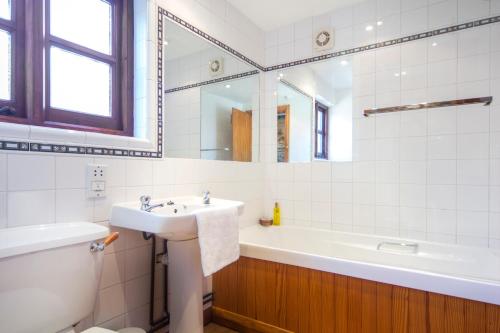 a bathroom with a sink and a tub and a toilet at Three Gates Farm Holiday Cottages in Huntsham
