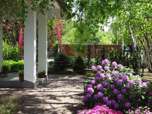 un jardín con flores púrpuras y un pabellón en Hotel Flora, en Łódź