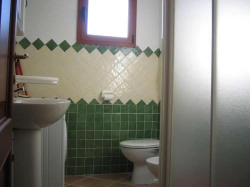 een groen betegelde badkamer met een toilet en een raam bij Recidence il gabbiano in Valledoria