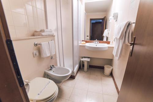 a white bathroom with a toilet and a sink at Hotel Everest Arco in Arco
