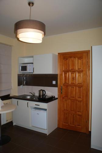 a kitchen with a sink and a microwave and a door at Willa Kasztelańska in Porąbka