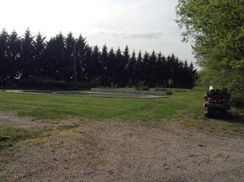 a field with a pile of logs in the grass at La Pierre Blanche in La Sauvetat-sur-Lède