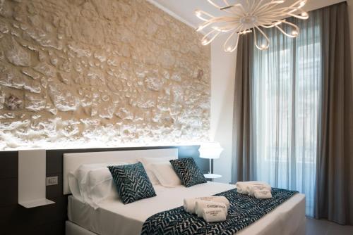 a bedroom with a white bed and a chandelier at Caportigia Boutique Hotel in Siracusa