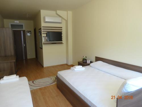 a hotel room with a bed and a flat screen tv at Hotel Lago Peshtera in Peshtera