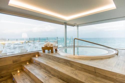 a bath tub in a room with a view of the ocean at Hotel Meridional in Guardamar del Segura