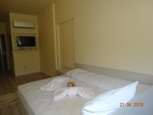 a white bed with a robe on top of it at Hotel Lago Peshtera in Peshtera