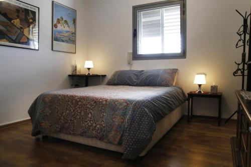 a bedroom with a bed and a window and two lamps at Herzelia Rooftop Special 2 Room Apartment in Herzliya
