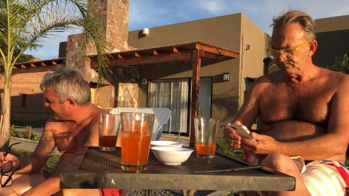 dos hombres sentados en una mesa mirando un celular en El esparto, en Lobos