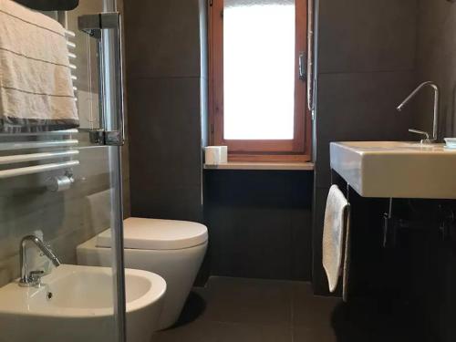 La salle de bains est pourvue de toilettes, d'un lavabo et d'une fenêtre. dans l'établissement Bardonecchia Holidays, à Bardonnèche