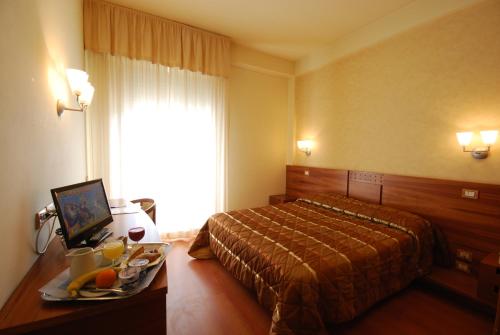 una camera d'albergo con letto e tavolo con vassoio di cibo di Hotel Gala a Pesaro