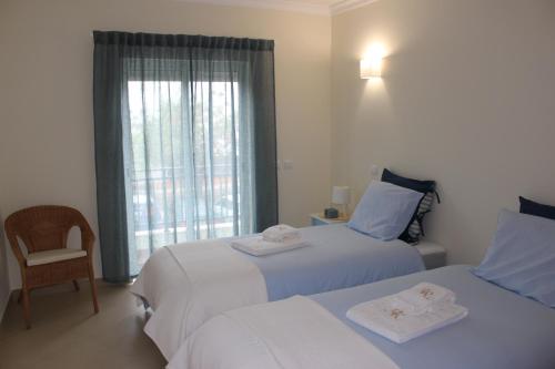 a hotel room with two beds and a window at Alta da Ria House in Cabanas de Tavira