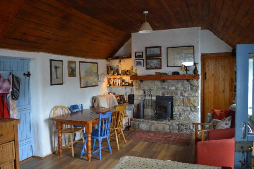 a living room with a table and a stone fireplace at Marsh Cottage F91 N4A9 in Moneygold