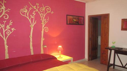 a bedroom with a red wall with trees painted on it at Il rifugio nel parco in Villetta Barrea