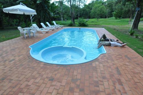 a person laying on the ground next to a swimming pool at IguassuEcoHostel - Eco Suítes - Hostel mais próximo das Cataratas in Foz do Iguaçu